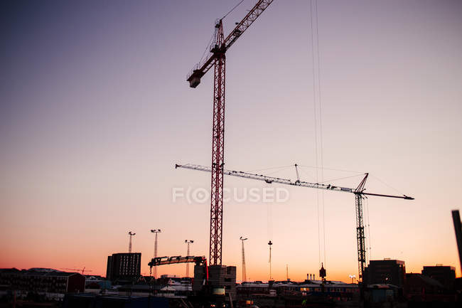 Cranes in harbor at sunset — Stock Photo