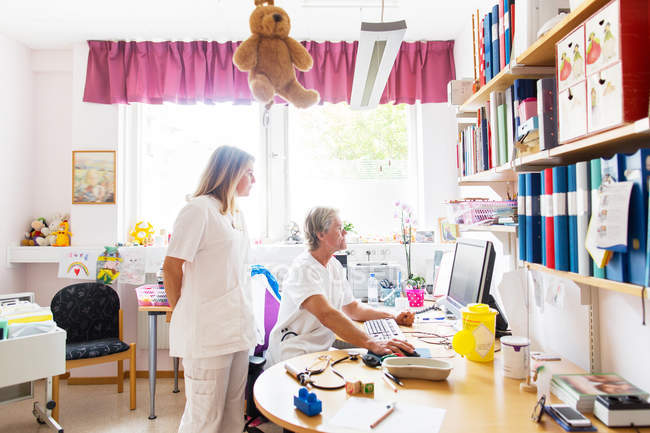 Médico e enfermeiro olhando para monitor de computador — Fotografia de Stock