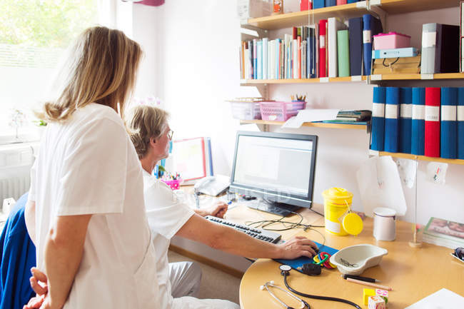 Medico e infermiere guardando monitor del computer — Foto stock