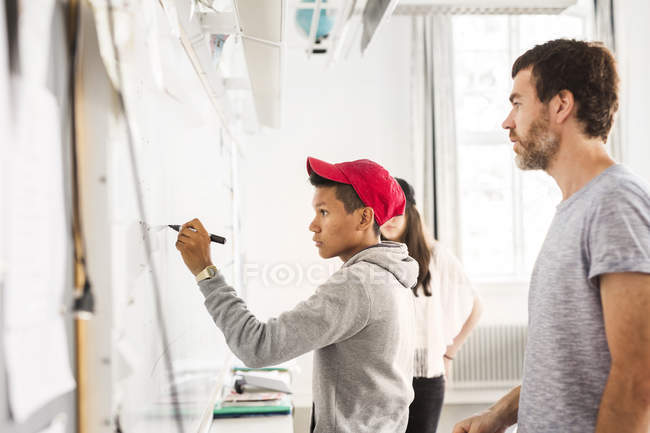 Student writing on whiteboard — Stock Photo