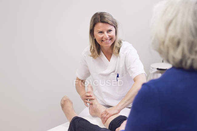 Médico sonriendo a paciente mayor - foto de stock