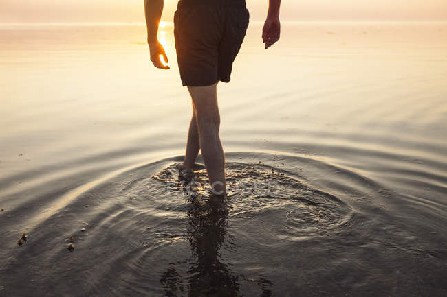 Hombre en pantalones cortos vadeando en el mar - foto de stock