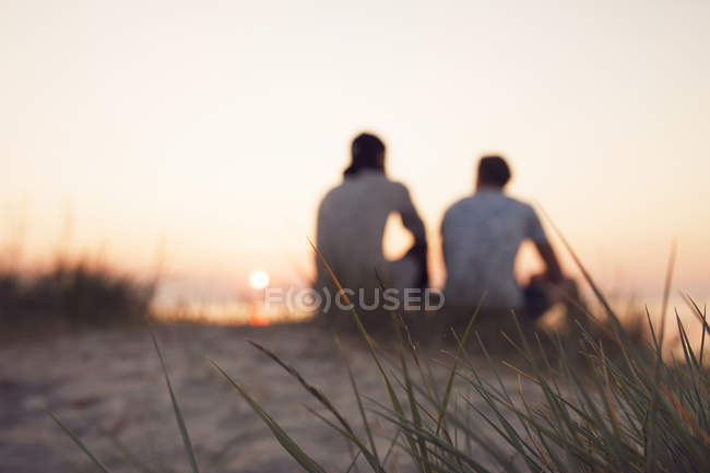 Dos jóvenes sentados en la playa - foto de stock