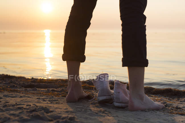 Чоловік стоїть біля моря на заході сонця — стокове фото