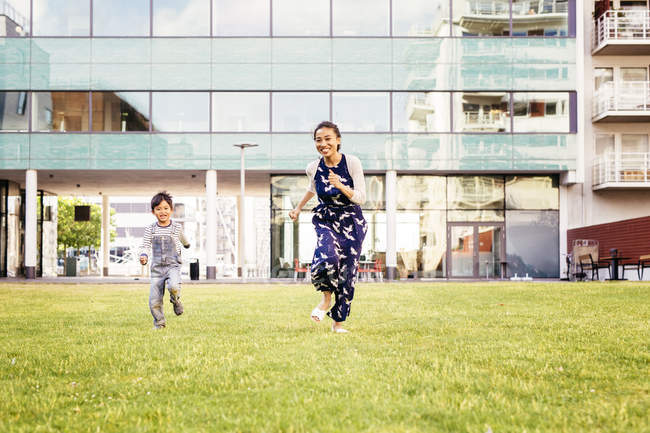 Mãe correndo com filho na grama — Fotografia de Stock