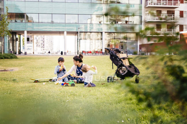 Madre con hijos sentados en la hierba - foto de stock