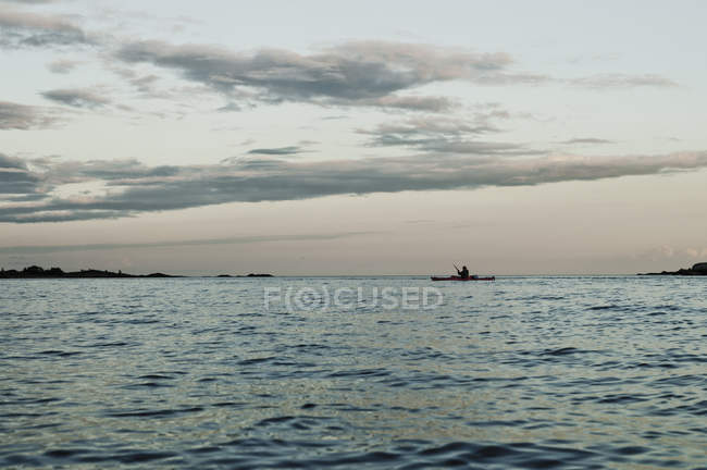 Морской пейзаж с силуэтом гребной лодки — стоковое фото
