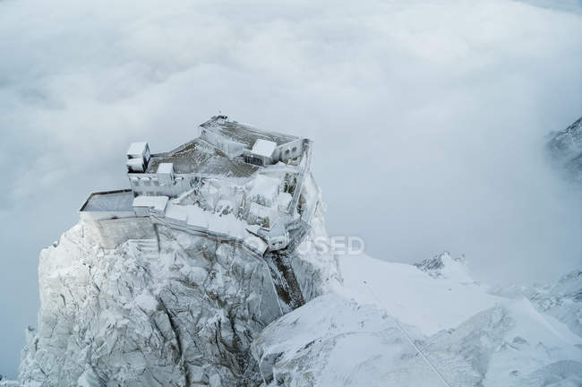 Сніговий покритий будинок на скелі — стокове фото