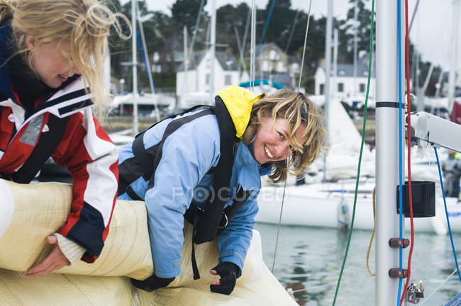 Women rolling up sail on sailboat — Stock Photo