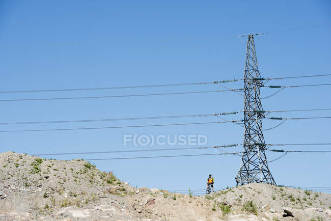 Homme debout sous un pylône électrique — Photo de stock