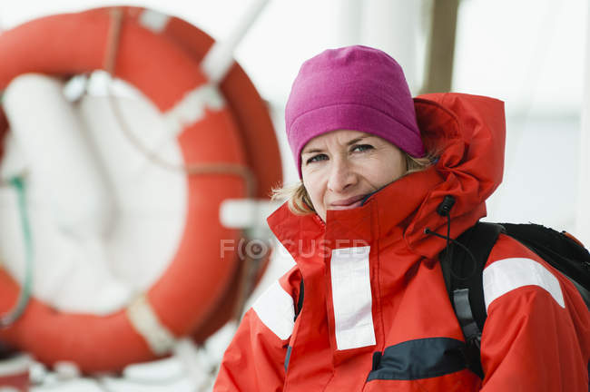 Woman in red jacket with backpack standing on boat — Stock Photo
