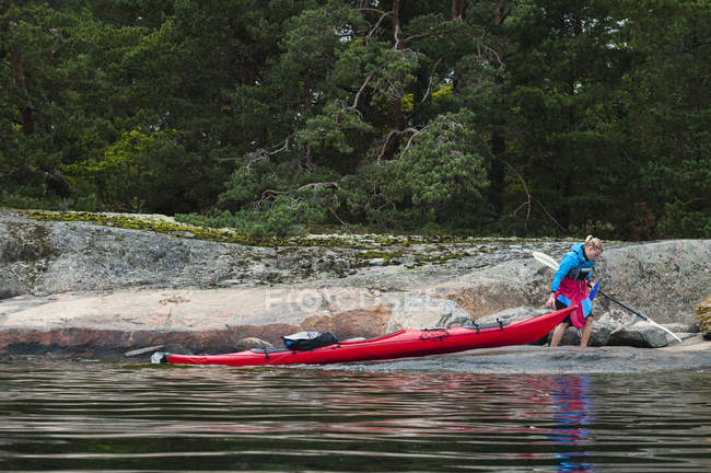 Woman pulling kayak on lakeshore — Stock Photo