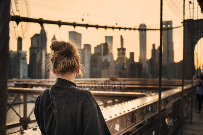 Жінка стоїть на мосту і дивиться на міський пейзаж — стокове фото