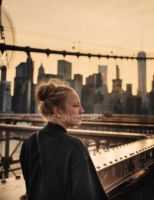 Mulher de pé na ponte e olhando para longe — Fotografia de Stock