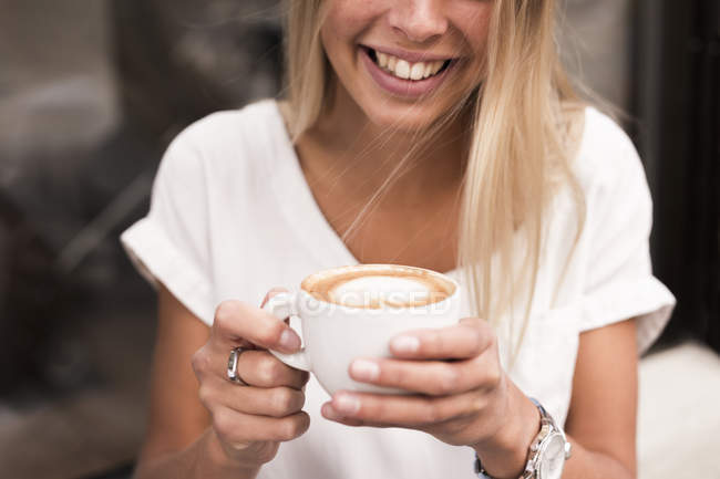 Lächelnde Frau mit Cappuccino — Stockfoto