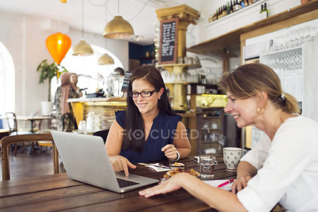 Femmes d'affaires utilisant un ordinateur portable pendant le déjeuner — Photo de stock