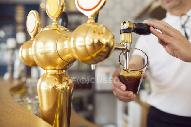 Cantinero vertiendo cerveza en un vaso - foto de stock