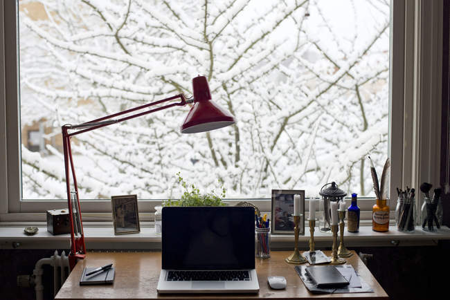 Lâmpada e laptop na mesa por janela — Fotografia de Stock