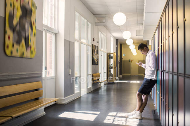 Jovem estudante em pé no corredor — Fotografia de Stock