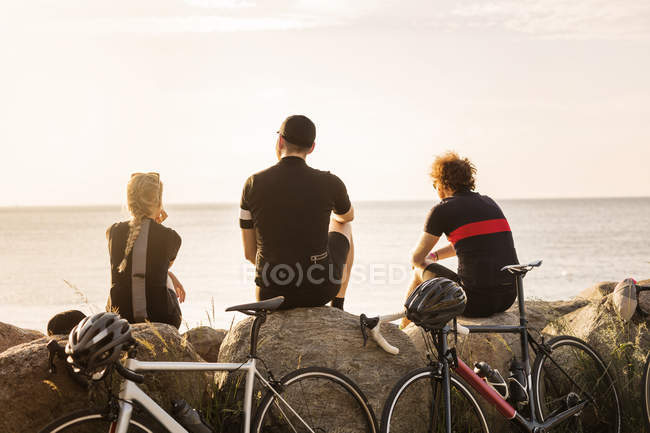 Cyclistes assis sur le littoral au coucher du soleil — Photo de stock