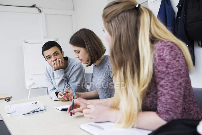 Estudiantes estudiando en el escritorio en el aula - foto de stock