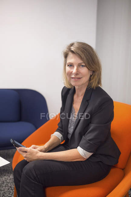 Frau sitzt und hält Telefon — Stockfoto