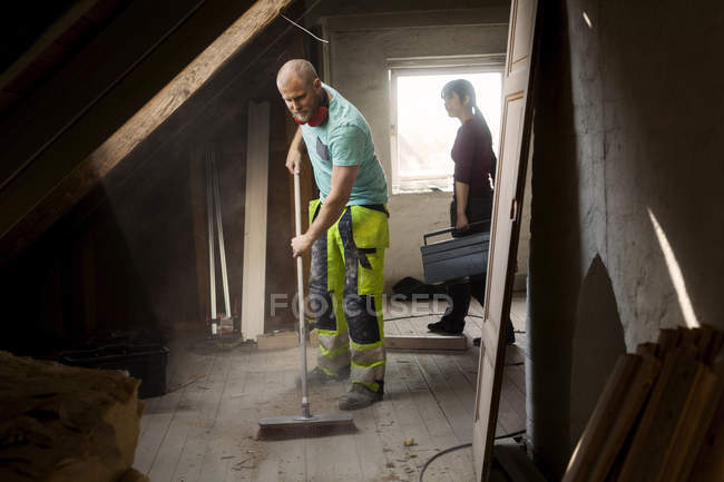Homem varrendo sótão velho — Fotografia de Stock