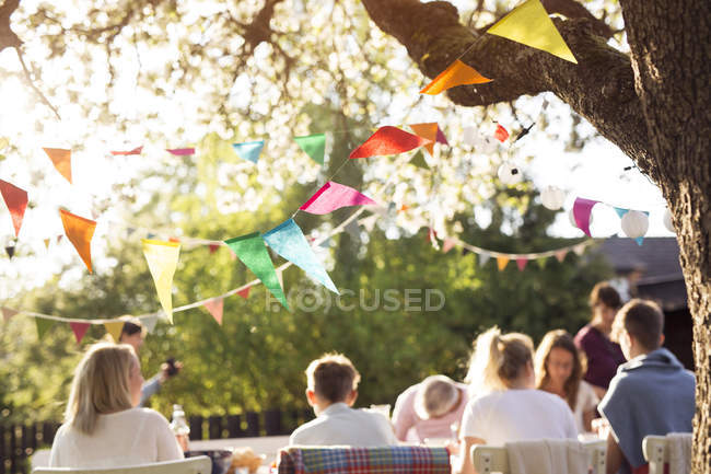 Rear view of family sitting at dinner table at garden party in back yard — Stock Photo