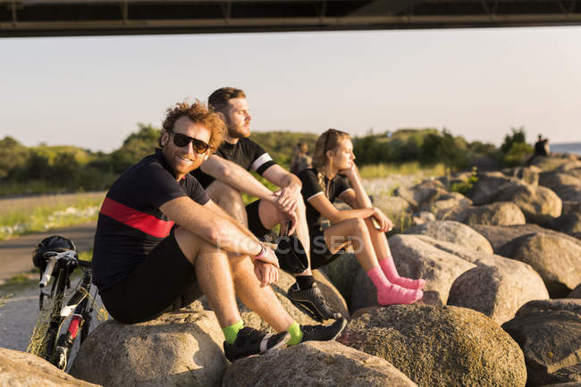 Cyclists sitting on coastline at sunset — Stock Photo