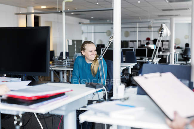 Усміхнена жінка сидить в офісному інтер'єрі — стокове фото