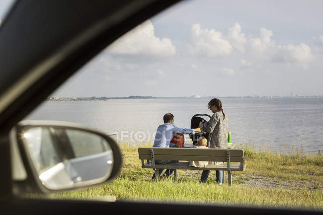 Padres con hijo sentado en el banco - foto de stock