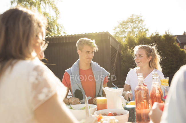 Adolescente casal sentado à mesa de jantar no jardim festa no quintal — Fotografia de Stock