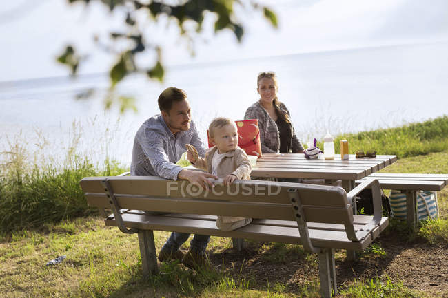Família sentada na mesa de piquenique — Fotografia de Stock