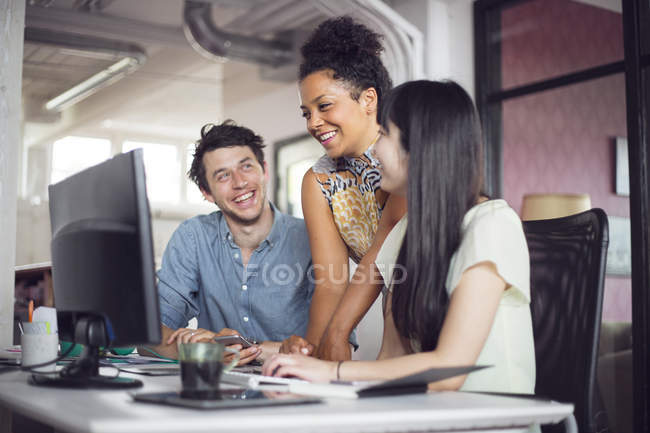 Colaboradores sonriendo frente a la computadora - foto de stock