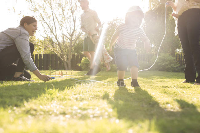 Girl skipping rope in garden with parents — Stock Photo