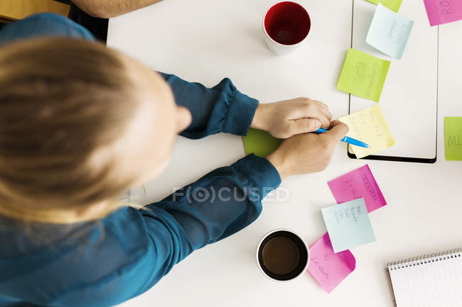 Overhead view of woman writing adhesive notes during business meeting — Stock Photo