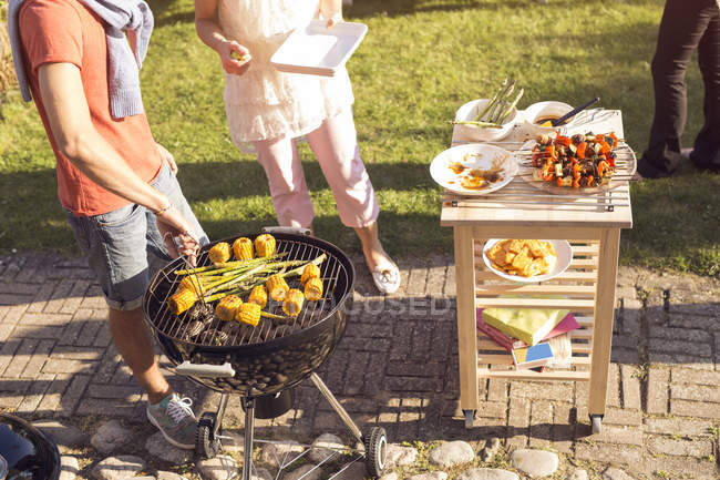 Man turning vegetables on barbecue grill — Stock Photo