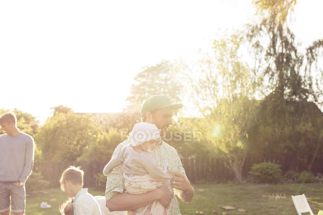 Отец носит девочку в саду — стоковое фото