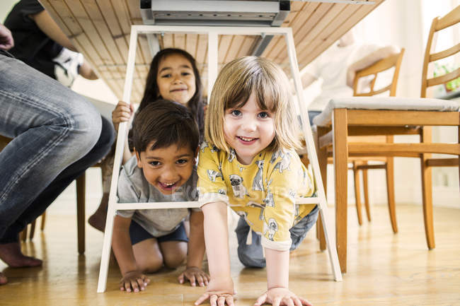 Niños jugando debajo de la mesa - foto de stock