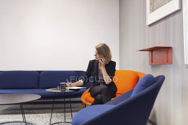 Woman writing and making call — Stock Photo
