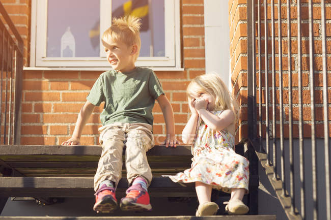 Boy and girl sitting on stairs and looking away — Stock Photo