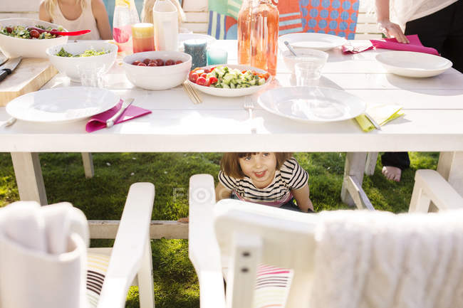 Mädchen versteckt sich bei Gartenparty unter Tisch — Stockfoto