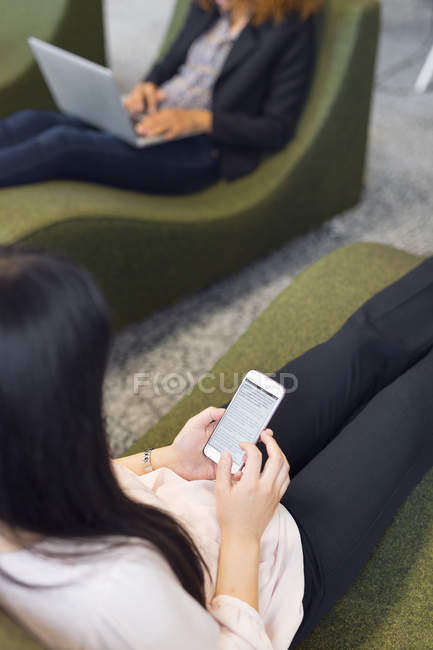Women using smartphone and laptop — Stock Photo