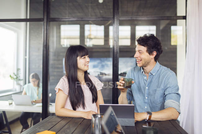 Співробітники розмовляють і посміхаються з кавою — стокове фото