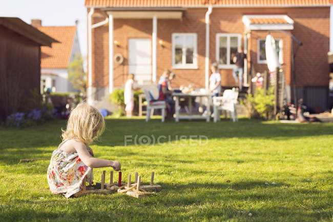 Menina brincando com brinquedo de madeira na grama — Fotografia de Stock