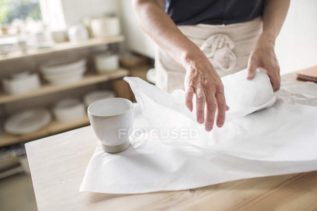 Potter wrapping pottery in paper — Stock Photo