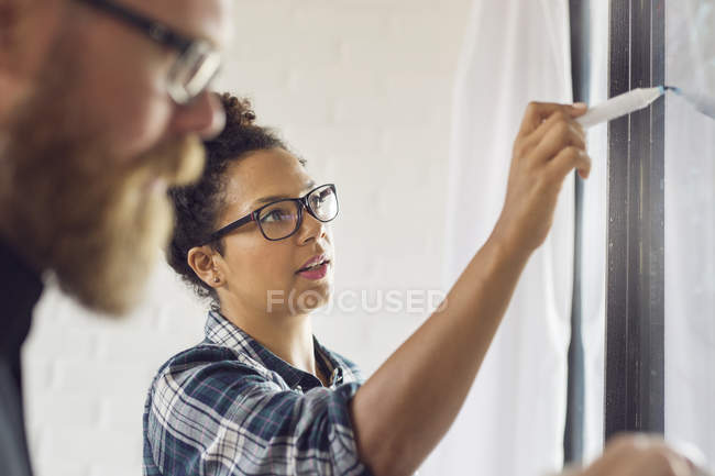 Donna che scrive su parete di vetro — Foto stock
