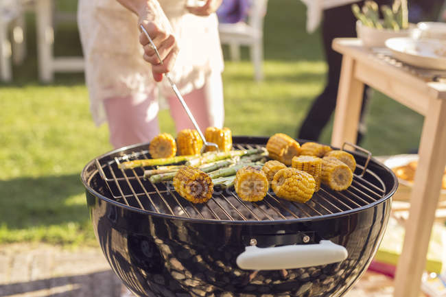 Woman turning vegetables on grill — Stock Photo