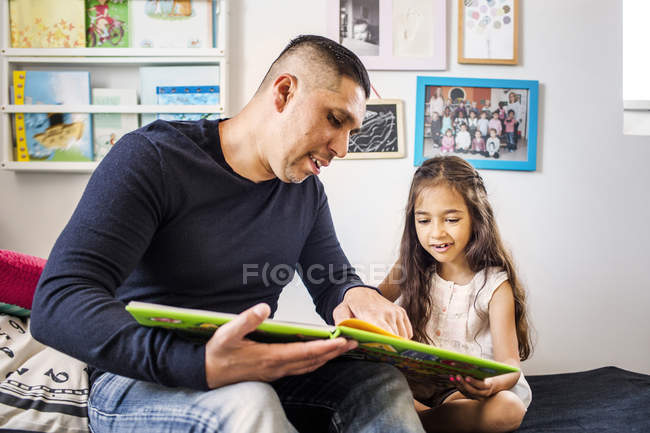 Hombre leyendo libro a chica - foto de stock