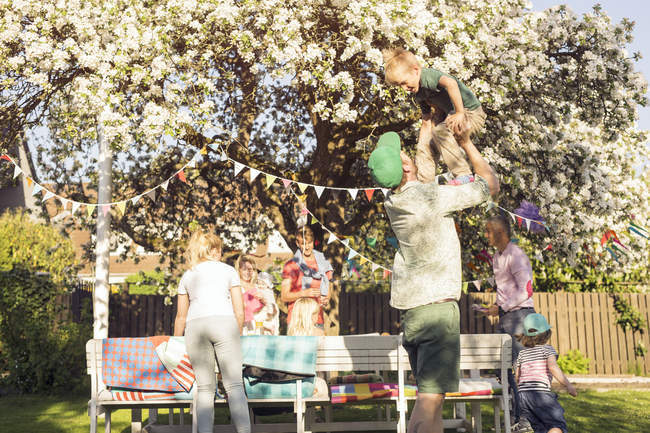 Люди з дітьми на пікніку в саду з квітучим деревом — стокове фото